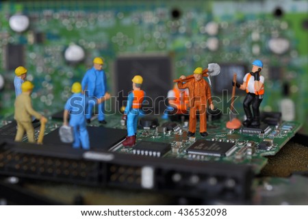 Selective focus of miniature engineer and worker fixed problem on chips and computer mainboard as business and industrial concept.