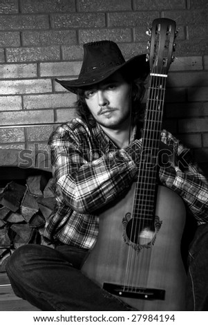 young man in a cowboy hat with guitar in b&w