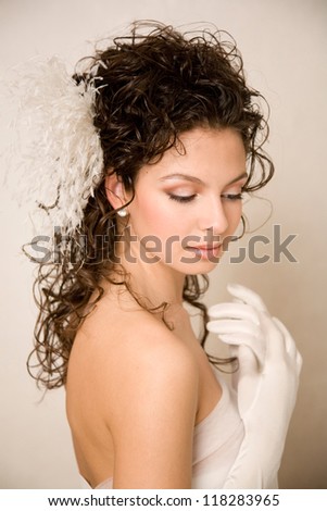 Young beautiful bride with her hands near her chest  and feather hairpin in her hair