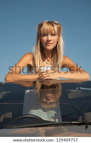 Sensual young woman is standing in the  sport car and looking away (car with right steering wheel)