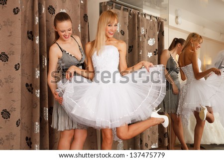 Two girlfriends  - A Bride-To-Be and  bridesmaid  - having fun -Trying On A Wedding Dress