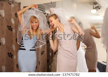 Two girlfriends  - A Bride-To-Be and  bridesmaid  - having fun -Trying On A Wedding veils