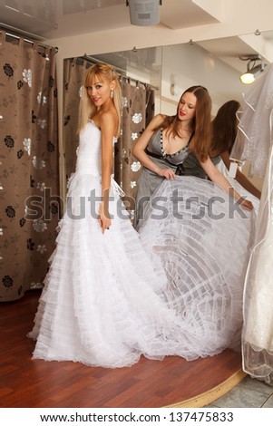 Two girlfriends  - A Bride-To-Be and  bridesmaid Trying On A Wedding dress