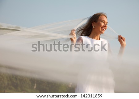 Young bride is holding her flying veil