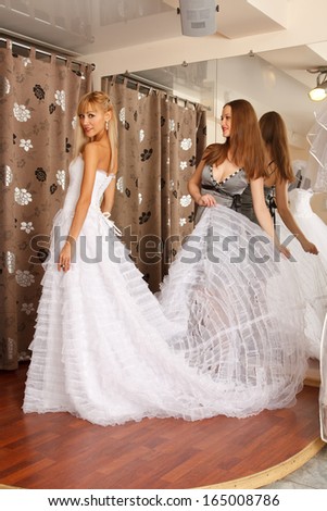 Two girlfriends  - A Bride-To-Be and  bridesmaid Trying On A Wedding dress