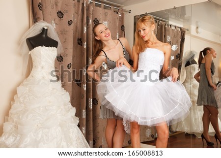 Two girlfriends  - A Bride-To-Be and  bridesmaid  - having fun -Trying On A Wedding Dress