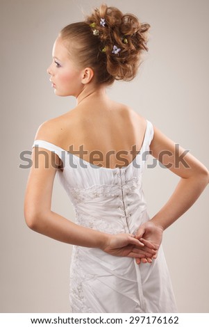 Young stylish bride holds her hands  behind her back