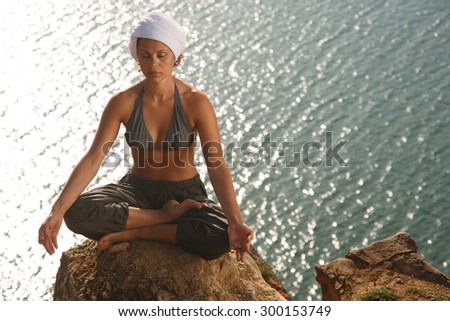 Real yoga instructor practicing on the rock near water line
