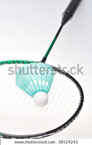 Closeup of a single badminton shuttle lying on a green and black racket, shallow DOF