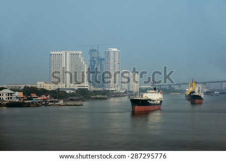 Cargo ship floating on chaow pra ya river with business building background - bangkok Thailand
