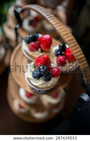 Mix of fruit berries topping on cup cake represent  Strawberry , raspberries , mulberries and blueberries decorate on wooden tray from top view