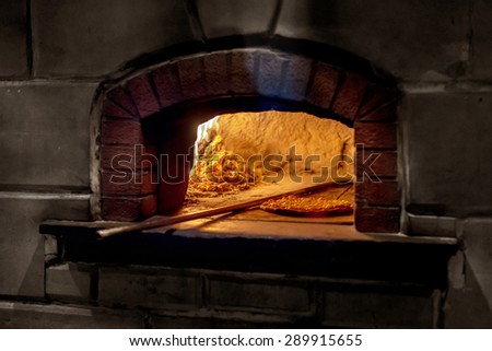 Baked pizza by the fire burn in  brick traditional vintage oven