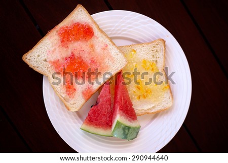Toasted bread with strawberry jam and orange jam with sliced water melon prepared for breakfast from top view