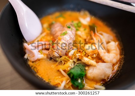 Close up of Thai Tom Yum spicy lime seafood noodle with mantis shrimp , squid , shrimp , crab , and fish fillet