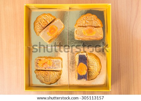 4 moon cakes in a Chinese mid-autumn festival in golden box and cut up half to show egg yolk