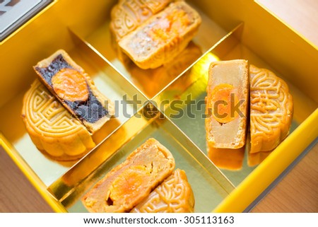 4 moon cakes in a Chinese mid-autumn festival in golden box and one cut up half to  egg yolk