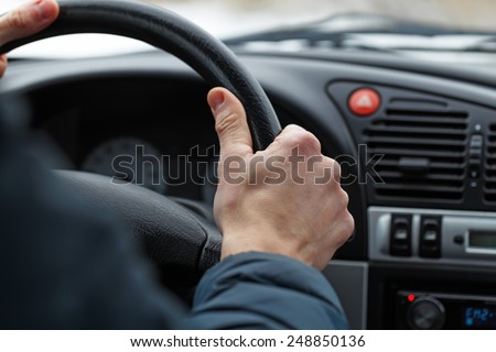 Close up of a male hand on steering wheel.