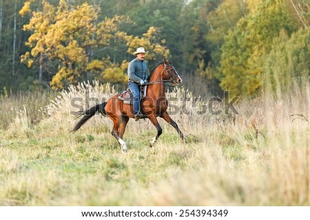 Man riding a horse in autumn landscape.