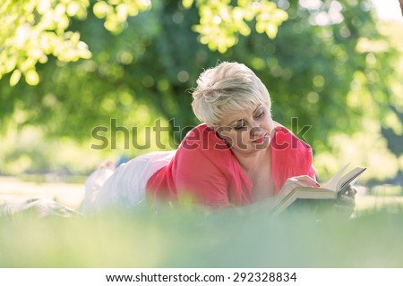 Beautiful woman reading book in city park.