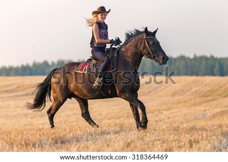 Cowgirl riding a horse at sunset.