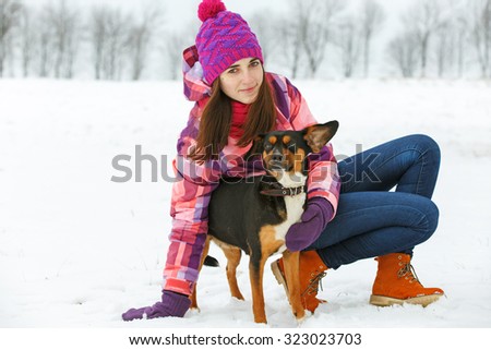 Young woman with a dog having fun at winter walk.