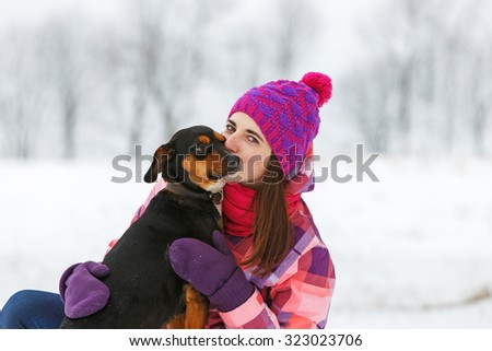 Young woman with a dog having fun at winter walk.