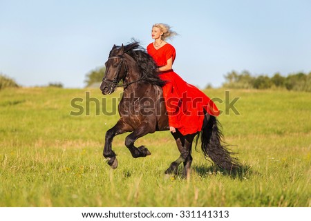 Young woman in red dress riding black horse bareback.