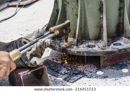 A black smith is making hole on steel plate by using gas and fire