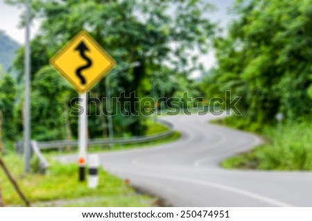 Abstract blur background  image of the road curved like a snake with warning sign