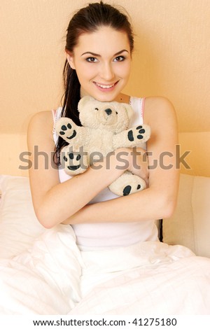 Young woman in her bed with teddy bear