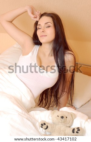 Beautiful young girl waking up in bed in the morning