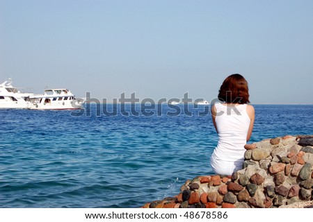 Woman from the back sitting near the ocean