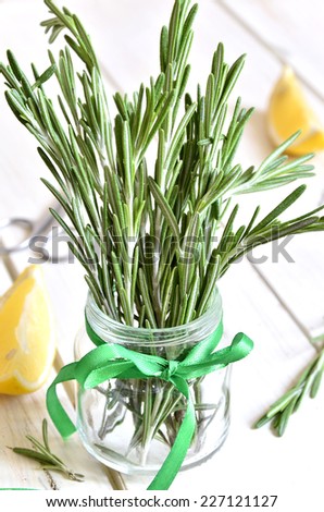 Bunch of rosemary in a jar on white wooden table