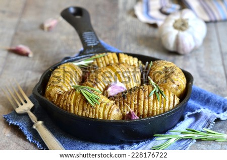 Baked jacket potatoes with garlic and rosemary in a pan.
