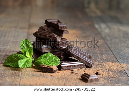 Stack of chocolate slices with mint leaf on a wooden table.