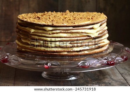 Layered honey cake with custard on a wooden background.