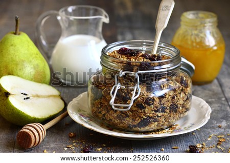 Granola from rye and oat flakes with dried cranberries and coconut in a glass jar on wooden table.