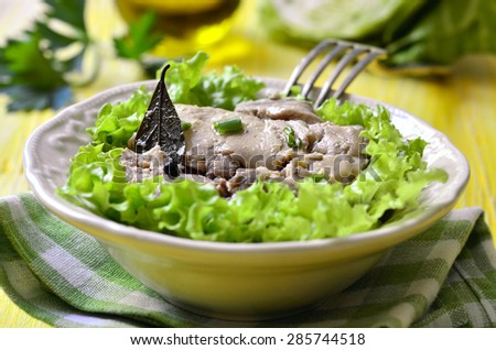 Cod liver in a bowl on yellow wooden table.