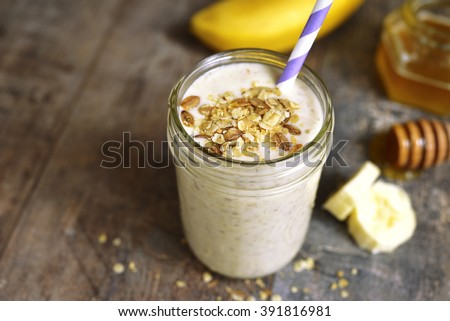 Banana smoothie with oat in a jar on rustic wooden background.
