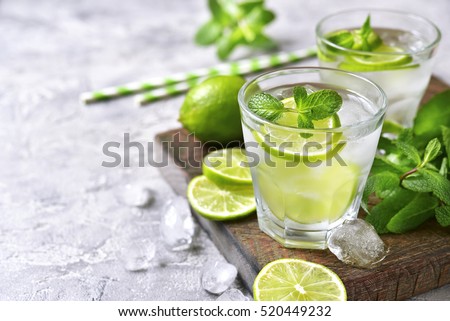 Cold refreshing summer lemonade mojito in a glass on a grey concrete or stone background.