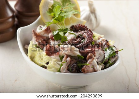 Octopus salad with lemon slice and lettuce