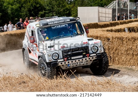 Chichester, West Sussex, UK - June 29, 2014: Landrover rally vehicle slides around corner with hay bails separating onlookers from the course