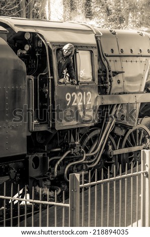 Alresford, Hampshire, UK - April 13, 2014: Train driver leans out of historic locomotive while reversing the train