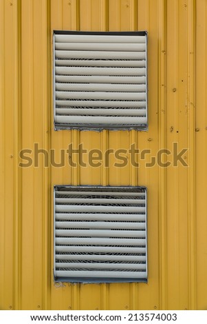 Two Stainless Steel Shutter Windows Covering Exhaust Fans With Background of Yellow Corrugated Plate.