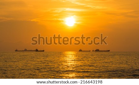 Beautiful Golden Sunset over The Ocean, With Fleet of  Cargo Ships Over the Horizon. The Air is a little foggy.