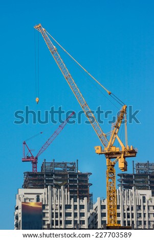 Yellow Tower Crane on Top of A Construction Site, With Another Red Crane on Top of A More Distant Building in Construction.