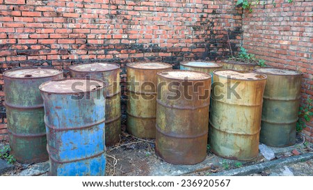 Rusty Barrels  of Green, Blue And Brown Colors Forsaken in The Corner of A Brick Wall.