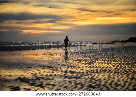 A boy walks on the beach silhouette sunset at seaside alone.