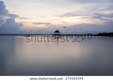 A wooden bridge leading to the sea on a beautiful sunset light.
