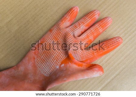 Orange rubber gloves on a brown background. Protective equipment when working with concrete.